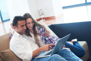 happy young relaxed couple working on laptop computer at modern home interior
